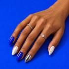 A hand on cobalt wearing Brainwave: cobalt, pearly white and silver almond nails.