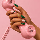 A hand in Green Flag nails holding a pink vintage phone receiver.
