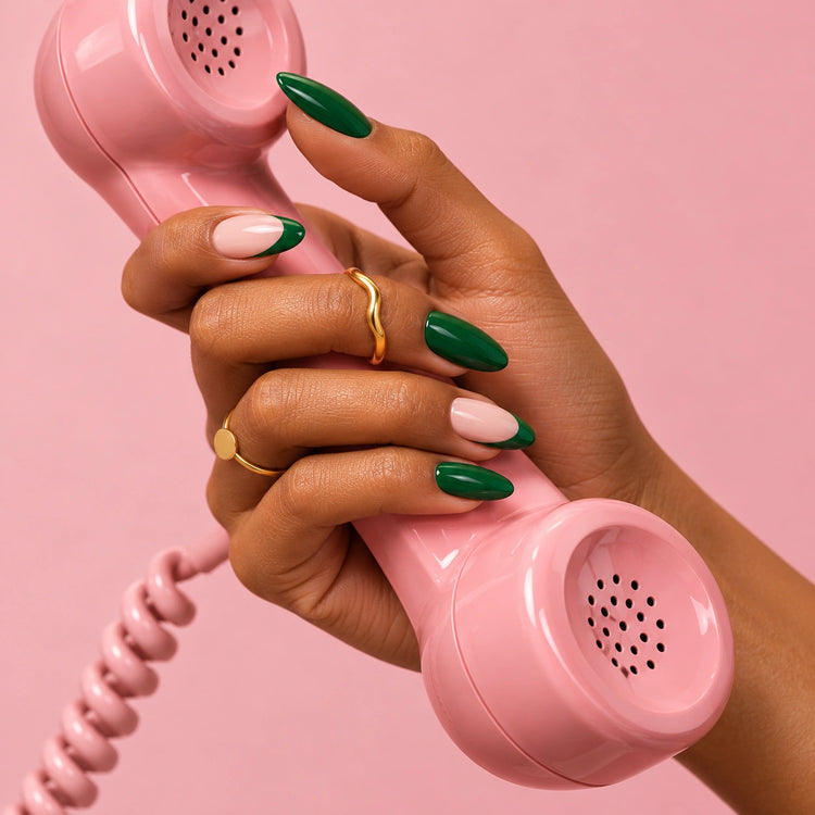 A hand in Green Flag nails holding a pink vintage phone receiver.