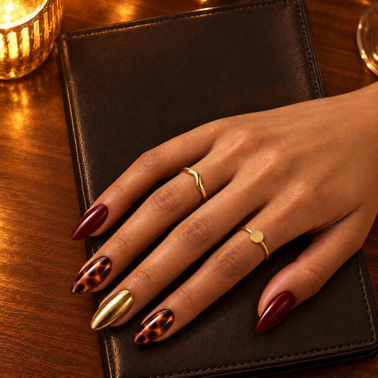 A hand in On Me nails resting on a leather bill folder on a café table, a candle glowing nearby.