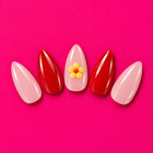 Shaadi Shift press-on nails fanned out on pink: pink and red, with a little yellow flower.