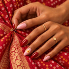 A hand in Shaadi Shift nails fixing a gold safety pin into a red bandhani dupatta.