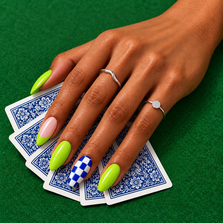 A hand in Wild Card nails over playing cards lying face down on green felt.