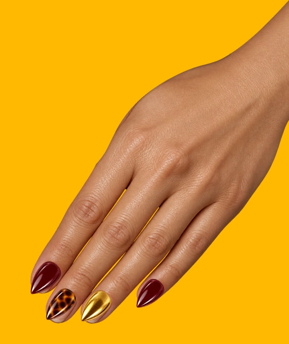 Illustration: a hand on mustard yellow wearing the On Me set: burgundy, tortoiseshell and gold nails.